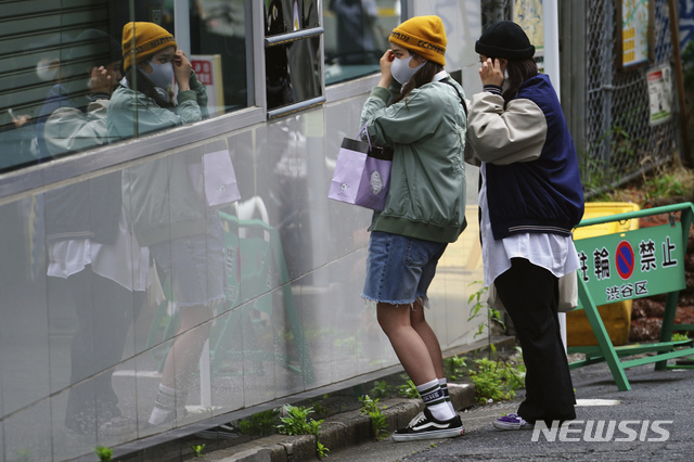 [도쿄=AP/뉴시스]일본의 황금연휴 '골든위크'가 시작되는 29일 도쿄 시부야 구역에서 코로나19 확산을 막기 위해 마스크를 쓴 여성들이 거리의 유리를 들여다보며 옷매무새를 고치고 있다. 일본이 히로히토 일왕의 생일인 29일부터 다음달 5일 어린이날까지 '골든위크'로 불리는 연휴를 맞는 가운데 수도권 4개 광역지방자치단체장은 '골든위크' 연휴를 집에서 보낼 것을 호소했다. 2021.04.29.