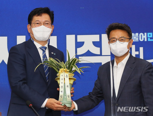 [서울=뉴시스]김진아 기자 = 송영길(왼쪽) 더불어민주당 신임 대표가 3일 서울 여의도 국회에서 이철희 청와대 정무수석으로 부터 문재인 대통령의 축하난을 전달받고 있다. (공동취재사진) 2021.05.03. photo@newsis.com