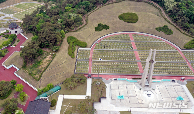 [광주=뉴시스] 류형근 기자 = 5·18민주화운동 41주기 기념식을 14일 앞둔 4일 오전 광주 북구 운정동 국립5·18민주묘지에서 북구청 신규공무원과 제27기 청년간부회의 직원들이 손태극기를 열사 묘역에 꽂고 있다. 2021.05.04. hgryu77@newsis.com