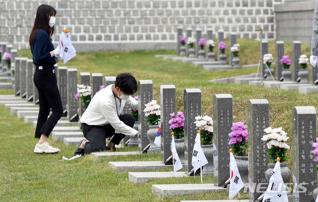 [광주=뉴시스] 류형근 기자 = 5·18민주화운동 41주기 기념식을 14일 앞둔 지난 4일 오전 광주 북구 운정동 국립5·18민주묘지에서 북구청 신규공무원과 제27기 청년간부회의 직원들이 손태극기를 열사 묘역에 꽂고 있다. 2021.05.04. hgryu77@newsis.com