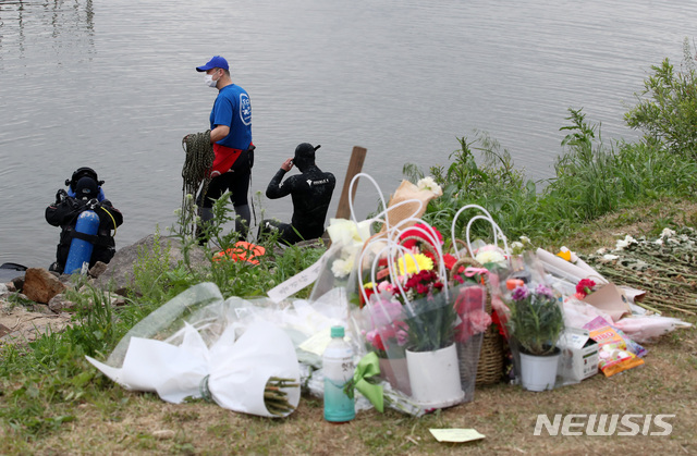 [서울=뉴시스]고범준 기자 = 지난 5월10일 서울 서초구 반포한강공원 수상택시 승강장 앞에서 민간 잠수부들이 숨진 대학생 A(22)씨의 친구 B씨의 휴대전화 수색 작업을 위해 준비하고 있다. 뒷편에는 A씨를 추모하기 위해 시민들이 가져온 꽃 등이 놓여있다. 2021.05.10. bjko@newsis.com