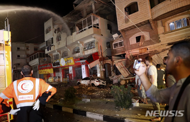 [가자지구=AP/뉴시스]12일 새벽(현지시간) 팔레스타인 가자지구에서 소방관들이 이스라엘군의 공습으로 불 타는 한 아파트 건물의 화재를 진압하고 있다. 이스라엘은 전날 무장 정파 하마스의 로켓포 공격에 대한 보복으로 가자 지구 공습을 이어갔다. 하마스는 장거리 미사일을 이용해 텔아비브 등의 주거용 건물 등을&nbsp; 타격하겠다고 경고하고 나서 전면전에 대한 우려가 커지고 있다. 2021.05.12.
