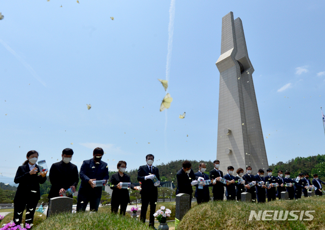 [광주=뉴시스] 김혜인 기자 = 광주5·18민주화운동 41주년을 닷새 앞 둔 12일 오전 광주 북구 운정동 국립 5·18민주묘지에서 유족과 전남 함평군 공무원이 518마리의 추모나비를 날리고 있다. 2021.05.13.hyein0342@newsis.com