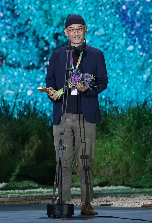 [서울=뉴시스]이준익 감독이 지난 13일 오후 경기 고양시 일산 킨텍스에서 열린 '제57회 백상예술대상' 시상식에서 영화부문 대상을 수상하고 있다. 이번 시상식은 지난해에 이어 코로나19 상황을 감안해 무관중으로 열렸다. (사진=백상예술대상 사무국 제공) 2021.05.14. photo@newsis.com *재판매 및 DB 금지