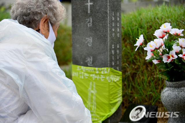 [광주=뉴시스] 김혜인 기자 = 5·18민주화운동 41주기를 하루 앞둔 17일 광주 북구 운정동 국립 5·18민주묘지 내 김경철 열사의 묘 앞에서 열사 어머니가 주저앉아 영정을 보고 있다. 2021.05.17. hyein0342@newsis.com