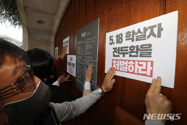 [서울=뉴시스]김형수 기자 = 5.18 민주화운동 41주년을 맞아 서울 서대문지역 여러 단체들이 18일 오후 전두환 전 대통령 연희동 사저 앞에서 기자회견을 가졌다.참석자들이 기자회견을 마친 후 전 씨의 자택 대문 앞에 '학살2' 시와 규탄 문구가 적힌 피켓을 부착하고 있다. (공동취재사진) 2021.05.18. photo@newsis.com