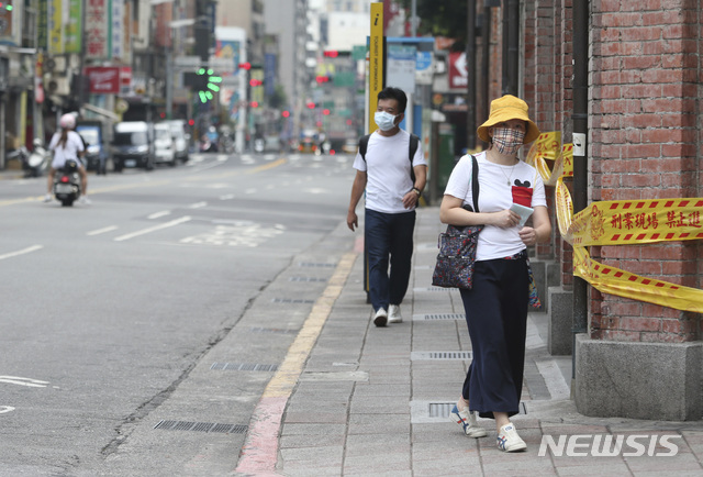 [타이베이=AP/뉴시스]대만의 코로나19 감염 경보가 3단계로 올라간 후 18일 한산한 타이베이 거리에서 마스크를 쓴 시민들이 걷고 있다. 지난주 대만의 코로나19 신규 확진자 수가 700명을 넘는 급증세를 보이면서 대만 정부는 뒤늦게 백신 수급에 동분서주하고 있다. 2021.005.18.