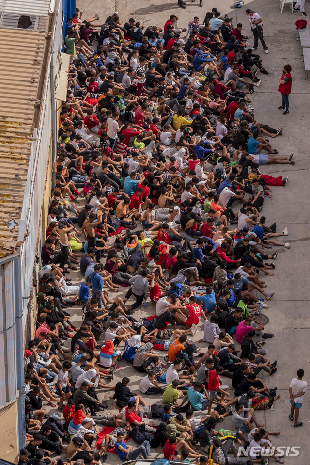  [세우타=AP/뉴시스]19일(현지시간) 보호자를 동반하지 않고 스페인 세우타로 넘어온 모로코 미성년자들이 임시 대피소로 사용하는 한 창고 밖에 모여 코로나19 검사를 기다리고 있다. 어린아이부터 성인에 이르는 수천 명의 모로코인이 수 km에 달하는 바다를 헤엄치거나 보트로 건너 스페인령 세우타로 들어오면서 이곳은 인도주의적 위기를 맞고 있다. 2021.05.20.&nbsp; 