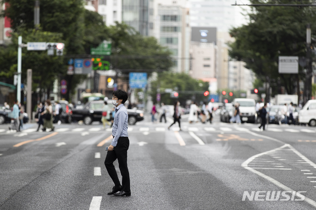 [도쿄=AP/뉴시스]21일 일본 도쿄의 긴자 쇼핑가에서 코로나19 확산 방지를 위해 마스크를 쓴 한 남성이 길을 건너고 있다. 2021.05.21.