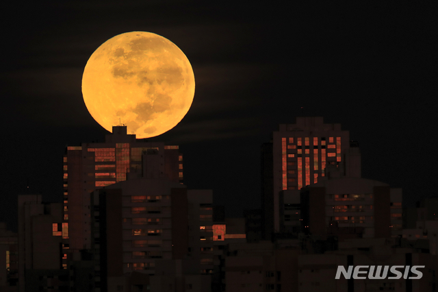 [브라질리아=AP/뉴시스]26일 새벽(현지시간) 브라질 브라질리아에서 건물들 뒤로 개기월식이 관측되고 있다. 이번 개기월식은 슈퍼문과 동시에 일어나면서 '슈퍼 블러드문'이 관측됐다. 2021.05.26.