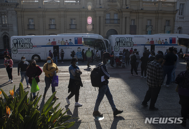 [산티아고=AP/뉴시스]26일(현지시간) 칠레 산티아고에서 코로나19 백신 접종을 하려는 시민들이 백신 접종소로 사용되는 버스 밖에서 순서를 기다리고 있다. 2021.05.27.