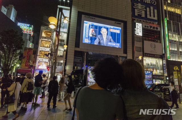 [도쿄=AP/뉴시스] 28일(현지시간) 일본 도쿄에서 행인들이 전광판을 통해 스가 요시히데(菅義偉) 총리 기자회견 장면을 보고 있다. 2021.05.29. 