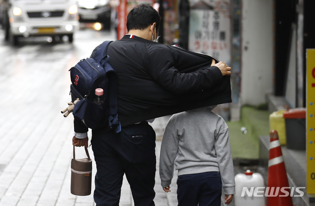 [서울=뉴시스]정병혁 기자 = 비가 내린 1일 오전 서울 중구 명동거리에서 한 어린이가 아빠 품에서 비를 피하고 있다. 2021.06.01. jhope@newsis.com