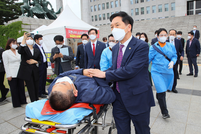 [서울=뉴시스]전신 기자 = 코로나19로 인한 소상공인과 자영업자의 손실피해에 대한 실질적 손해보상을 요구하며 천막농성 51일째와 단식농성 6일째를 이어온 최승재 국민의힘 의원이 1일 서울 여의도 국회 본청 앞 천막농성장에서 김기현 당 대표 권한대행 겸 원내대표의 권유로 들것에 실려 구급차로 이동하고 있다. (공동취재사진) 2021.06.01. photo@newsis.com