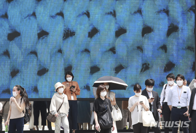 [도쿄=AP/뉴시스] 일본 수도 도쿄 시내에서 7일 코로나19 예방을 위해 마스크를 착용한 시민들이 횡단보도를 건너려고 신호를 기다리고 있다. 2021.06.07 
