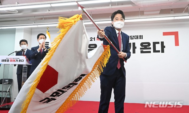 [서울=뉴시스]국회사진기자단 = 이준석 국민의힘 대표 당선자가 11일 오전 서울 영등포구 여의도동 국민의힘 당사에서 열린 전당대회에서 당기를 흔들고 있다. (공동취재사진) 2021.06.11. photo@newsis.com