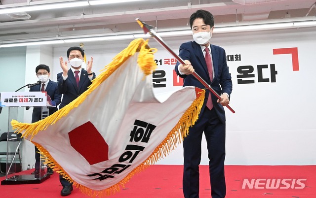 [서울=뉴시스]국회사진기자단 = 이준석 국민의힘 대표 당선자가 11일 오전 서울 영등포구 여의도동 국민의힘 당사에서 열린 전당대회에서 당기를 흔들고 있다. (공동취재사진) 2021.06.11. photo@newsis.com