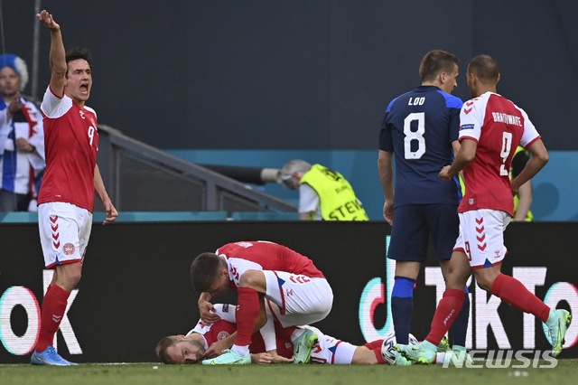 Denmark players run to Denmark&#039;s Christian Eriksen fallen on the ground during the Euro 2020 soccer championship group B match between Denmark and Finland at Parken Stadium in Copenhagen, Saturday, June 12, 2021. (Stuart Franklin/Pool via AP)