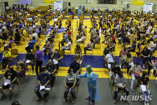 A health worker talks to one of people who wait to receive the Sinovac COVID-19 vaccine at Thai-Japan Bangkok Youth Center in Bangkok, Thailand, Monday, June 14, 2021. (AP Photo/Sakchai Lalit)