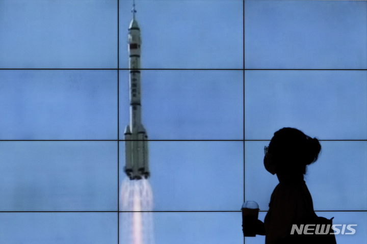 [베이징=AP/뉴시스] 일론 머스크가 이끄는 스페이스X의 위성통신 사업인 ‘스타링크’를 상대하기 위해 중국이 1만 3000개의 위성을 지구 저궤도에 쏘아 올릴 계획을 추진 중인 것으로 알려졌다. 사진은 2021년 6월17일 베이징의 한 쇼핑몰에서 한 여성이 위성 발표 장면이 방송되는 대형 스크린 앞을 지나가고 있는 모습. 2023.04.07