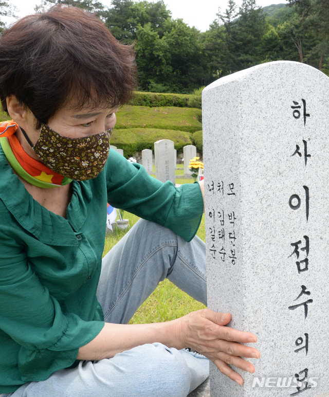 [전주=뉴시스]김얼 기자 = 한국전쟁 종료 한 달을 앞두고 북한의 폭탄에 사망한 故 하사 이점수 씨의 딸 이길수 씨가 21일 전북 전주시 낙수정 군경묘지에서 아버지의 이름과 자신의 이름이 적힌 묘비를 바라보고 있다. 2021.06.21. pmkeul@newsis.com