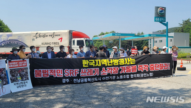 [장성=뉴시스]이창우 기자 = 22일 오전 한국지역난방공사가 전남 장성군 복합물류센터에 설치한 'SRF 임시 야적장' 방문에 나선 '나주 SRF 반대 공대위' 주민들이 입구에서 출입을 저지당하자 현수막을 펼친 채 구호를 외치고 있다. (사진=공대위 제공) 2021.06.22. photo@newsis.com