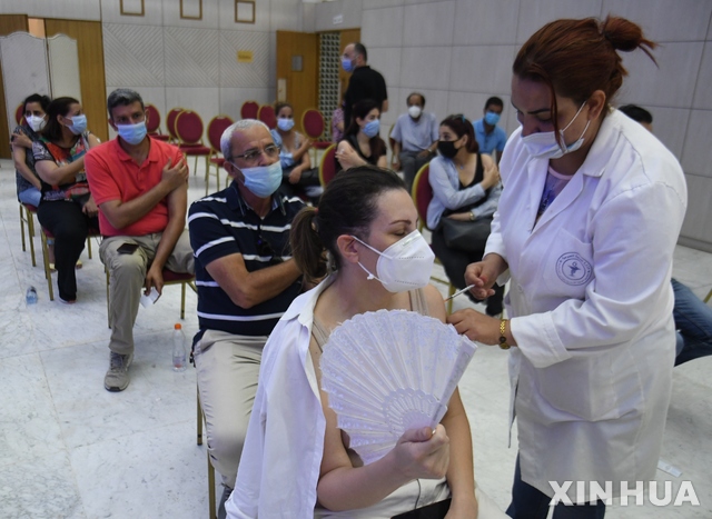 [ 튀니스( 튀니지)=신화/뉴시스] 6월 26일 튀니스 시내 코로나19 백신접종소에서 한 여성에게 의료진이 백신주사를 놓고 있다. 