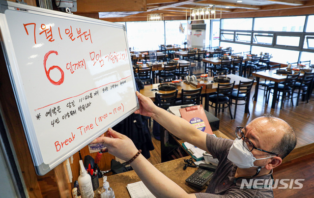 [서울=뉴시스]권창회 기자 = 새로운 사회적 거리두기 시행을 하루 앞둔 30일 오후 서울 시내 한 식당에서 점주가 '7월 1일부터 6인 모임 가능' 안내판을 거치하고 있다.  내달 1일부터 적용되는 새로운 사회적 거리두기는 수도권 지역 음식점 및 실내체육시설, 유흥시설 등의 영업 제한 시간이 밤 12시까지 늘어나고 사적 모임 인원이 2주간 최대 6인까지 허용된다. 2021.06.30. kch0523@newsis.com