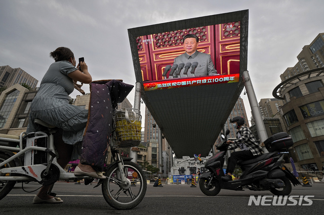 [베이징=AP/뉴시스]1일 중국 베이징의 톈안먼 광장에서 중국공산당 창당 100주년 기념행사가 열려 스쿠터를 탄 한 행인이 대형 비디오 스크린을 통해 연설하는 시진핑 주석의 모습을 찍고 있다. 2021.07.01.