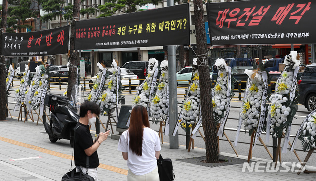 [서울=뉴시스] 이영환 기자 = 대우건설 매각작업이 추진되고 있는 7일 오후 서울 중구 대우건설 본사 앞에 매각을 규탄하는 근조화환과 현수막이 보이고 있다. 대우건설 최대주주인 KDB인베스트먼트는 대우건설 인수합병(M&A) 우선협상대상자로 중흥컨소시엄을 선정하고, 스카이레이크컨소시엄(DS네트워크 컨소시엄)을 예비협상대상자로 선정했다고 5일 밝혔다.2021.07.07. 20hwan@newsis.com