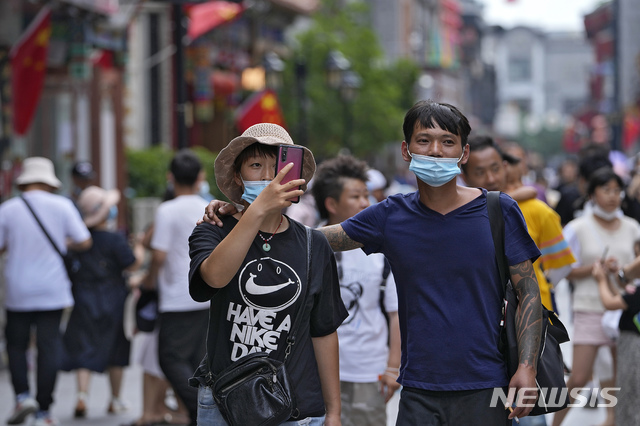 [베이징=AP/뉴시스] 8일(현지시간) 중국 베이징에서 코로나19 확산 방지를 위해 마스크를 착용한 연인이 인기 쇼핑 거리를 걸으며 사진을 찍고 있다.  2021.07.08