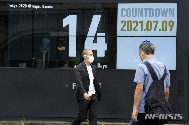 [도쿄=AP/뉴시스] 도쿄올림픽이 2주일 앞으로 다가온 가운데 9일 일본 도쿄 신바시역 부근에서 코로나19 예방을 위해 마스크를 착용한 시민들이 '올림픽 카운트다운 시계' 앞을 지나고 있다. 2021.07.10&nbsp; 