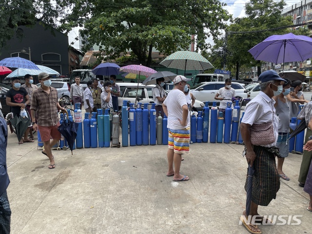 [양곤(미얀마)=AP/뉴시스]지난 11일 미얀마 양곤의 충전소에서 사람들이 산소 탱크를 들고 줄을 서 있다. 2021.07.13.photo@newsis.com