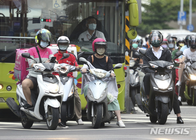 [타이베이=AP/뉴시스] 최근 들어 코로나19가 급속히 퍼진 대만 수도 타이베이 시내에서 12일 예방을 위해 마스크를 쓴 시민들이 스쿠터를 탄 채 신호등이 바뀌기를 기다리고 있다. 2021.07.14