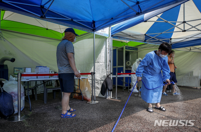 [서울=뉴시스] 정병혁 기자 = 폭염이 이어지고 있는 15일 오후 서울 양천구 파리공원에 설치된 찾아가는 선별진료소에서 의료진이 열을 식히기 위해 바닥에 물을 뿌리고 있다. 2021.07.15. jhope@newsis.com