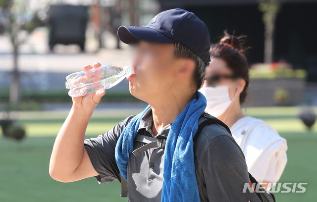 [서울=뉴시스] 권창회 기자 =폭염이 이어지고 있는 16일 오전 서울 중구 서울광장 인근에서 한 시민이 물을 마시며 이동하고 있다. 2021.07.16. kch0523@newsis.com