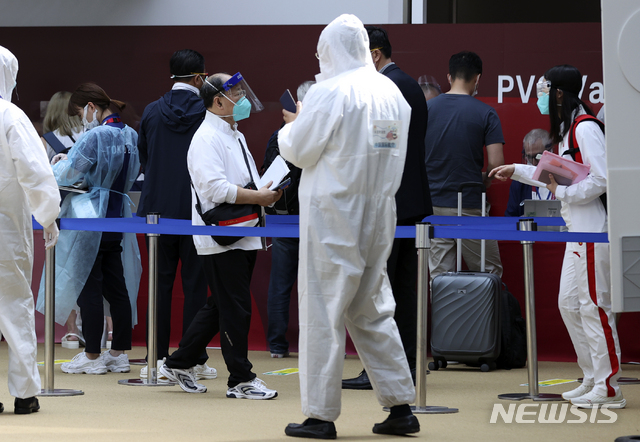 [나리타(일본)=뉴시스] 최진석 기자 = 18일 일본 나리타공항 사전올림픽등록카드(Pre-Valid Card·PVC) 카운터에서 도쿄올림픽 참가 외국인 미디어 관계자들이 사전올림픽등록카드 활성화 하고 있는 뒤로 방역복을 입은 공항 관계자가 보이고 있다. 2021.07.18. myjs@newsis.com