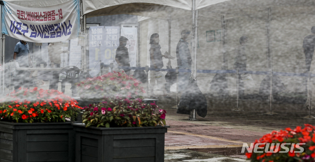 [서울=뉴시스] 정병혁 기자 = 19일 오전 서울 마포구 서강대역 광장에 설치된 임시선별검사소에서 마포구 관계자들이 열을 식히기 위해 선별검사소 주변에 물을 뿌리고 있다. 2021.07.19. jhope@newsis.com