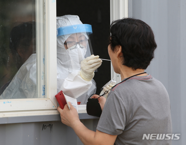 [강릉=뉴시스] 김경목 기자 = 지난 19일 오후 강릉시 보건소 공무원이 강원 강릉시 유천택지 임시선별진료소에서 코로나19가 의심되는 시민의 신체에서 검체를 채취하고 있다. 2021.07.19. photo31@newsis.com