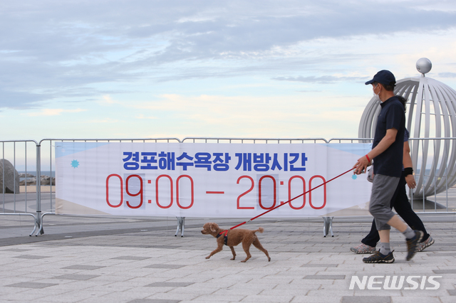 [강릉=뉴시스] 김경목 기자 = 사회적 거리두기 4단계가 시행된 첫날인 19일 오후 강원도 강릉시 경포해수욕장 개방시간이 오전 9시에서 오후 8시로 변경된 것을 알리는 현수막이 경포해수욕장 중앙통로 펜스에 게시돼 있다. 2021.07.19. photo31@newsis.com
