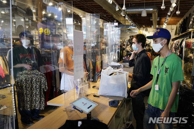 [로스앤젤레스=AP/뉴시스] 19일(현지시간) 미 캘리포니아주 로스앤젤레스(LA)의 페어팩스 구역에 있는 한 상점에서 마스크를 착용한 직원과 손님들이 계산대에서 결제하고 있다. LA 카운티는 최근 증가하는 코로나19 확진 사례로 실내 마스크 사용을 다시 의무화했다. 2021.07.20.