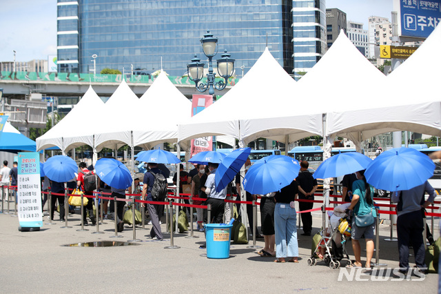 [서울=뉴시스] 김선웅 기자 = 전국 대부분 지역에 폭염 특보가 내려진 21일 오후 서울역광장 선별검사소에서 시민들이 검사를 받기 위해 우산을 쓰거나 천막 아래서 기다리고 있다 2021.07.21. mangusta@newsis.com