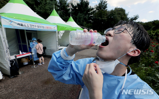 [서울=뉴시스] 김병문 기자 = 전국에 폭염특보가 발효된 지난 21일 오후 서울 양천구 파리공원 안에 설치된 코로나19 임시선별검사소에서 의료진이 물을 마시고 있다. 2021.07.21. dadazon@newsis.com