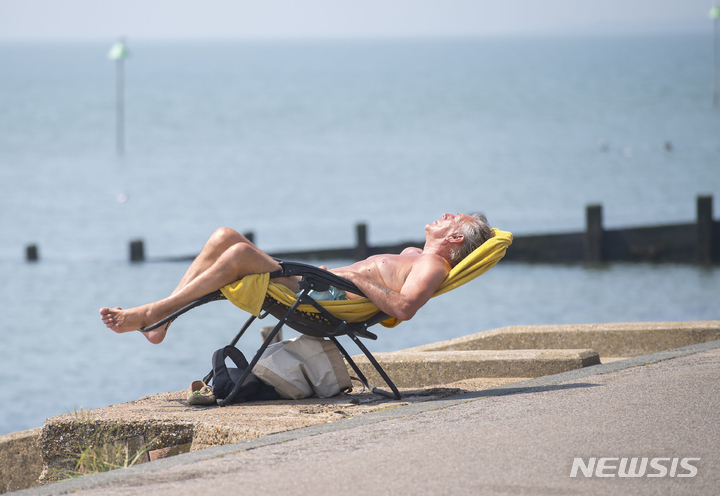 [사우스엔드=AP/뉴시스]지난 7월21일(현지시간) 영국 에식스주 사우스엔드 한 해변에서 일광욕을 즐기는 남성 