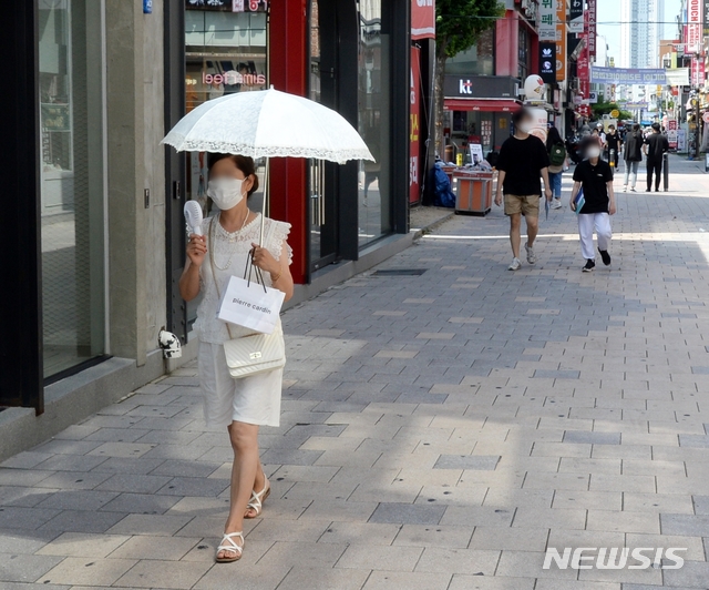 [청주=뉴시스] 조성현 기자 = 1년 중 가장 덥다는 절기 '대서(大暑)'인 22일 오후 충북 청주시 상당구 성안길에서 시민 한 명이 양산과 휴대용 선풍기를 들고 길을 걸어가고 있다. 2021.07.22. jsh0128@newsis.com 