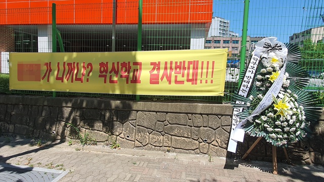 [과천=뉴시스] 변근아 기자= 과천 A초등학교 앞에 혁신학교 추진 결정에 반대하는 학부모들이 내걸은 현수막과 조화가 놓여있다. 2021.07.22. gaga99@newsis.com *재판매 및 DB 금지