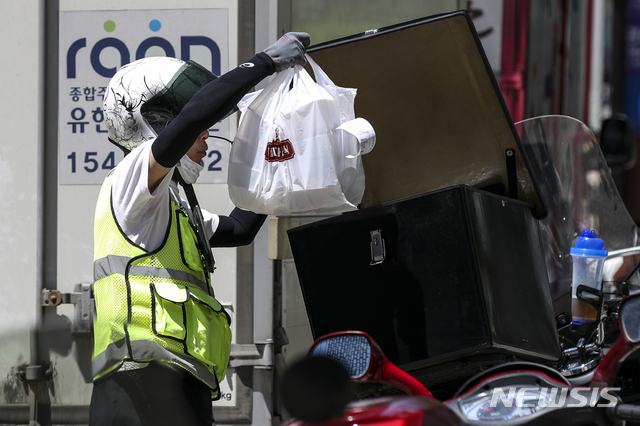 [서울=뉴시스] 정병혁 기자 = 서울 종로구 골목에서 한 배달 기사가 오토바이에 음식을 넣고 있다. 2021.07.22. jhope@newsis.com 이 사진은 기사 내용과 직접적 관련 없음