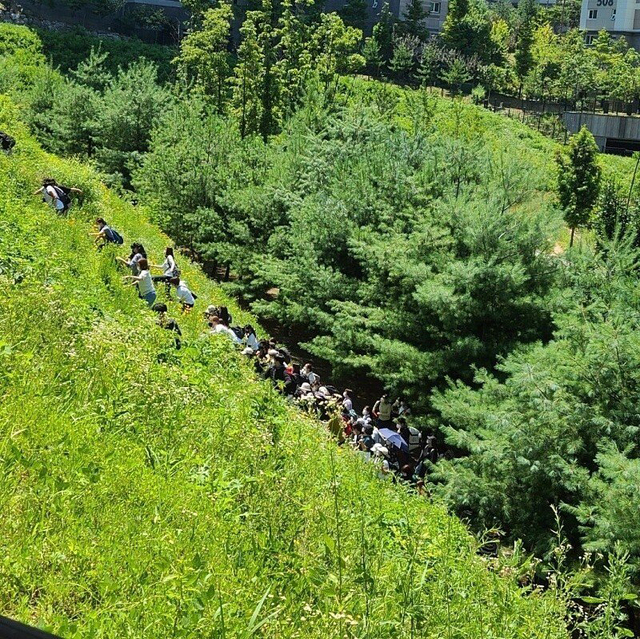 [서울=뉴시스] 전국민주노동조합총연맹(민주노총)이 23일 강원도 원주 혁신도시 국민건강보험공단 인근 언덕을 오르고 있다. 이들은 이날 국민건강보험공단에서 대규모 집회를 열 예정이였지만 경찰의 제지에 집회 장소가 막히자 언덕을 올랐다. (사진=독자 제공) 2021.07.23. photo@newsis.com