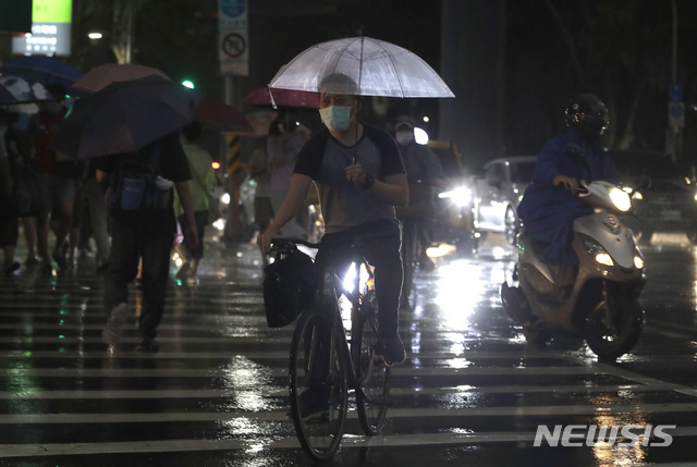 [타이베이=AP/뉴시스] 제6호 태풍 인파가 접근하면서 폭우가 쏟아지는 대만 수도 타이베이 시내에서 23일 밤 코로나19 예방을 위해 마스크를 착용한 시민들이 자전거와 스쿠터를 타거나 바쁜 걸음으로  횡단보도를 건너고 있다. 2021.07.24 