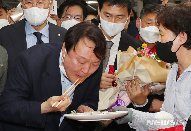 [부산=뉴시스] 야권 대권주자인 윤석열 전 검찰총장이 27일 부산 중구 자갈치시장을 방문, 한 상인이 건넨 전복회를 맛보고 있다. 2021.07.27. (부산사진공동취재단). photo@newsis.com